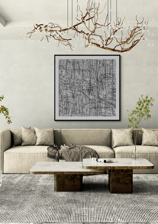 Reel by Priit Ruttas in a black frame above a beige sofa under a branch chandelier