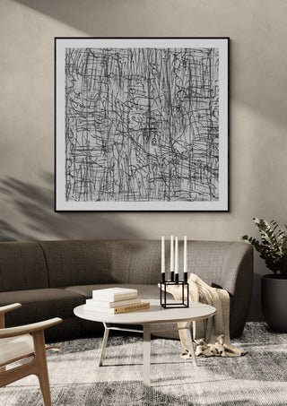 Reel by Priit Ruttas in a black frame above a grey sofa with candlesticks