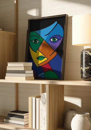 Mosaic of the Psyche by Bibi in a dark frame on a wooden shelf beside books and a lamp