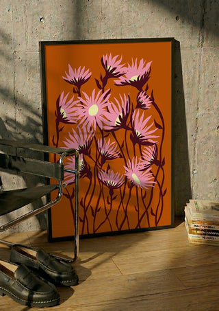 Whimsical flowers by Astrid Lind in a black frame leaning against a concrete wall by a steel chair