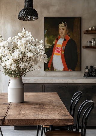 Fast Food King by Dikhotomy in a black frame above a rustic table with white flowers