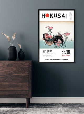 Framed print of Hokusai's "Cock and Flower" artwork hanging on a modern room wall above a wooden dresser.