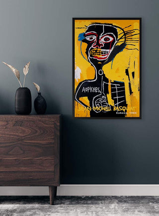Cabeza by Jean-Michel Basquiat artwork on a yellow background, displayed above a dark wooden dresser.