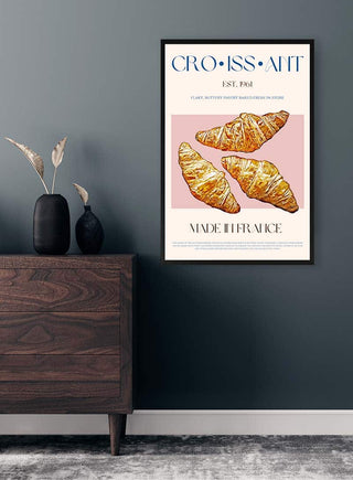 Framed croissant print with three illustrated croissants and French text, displayed on a wall above a dresser.