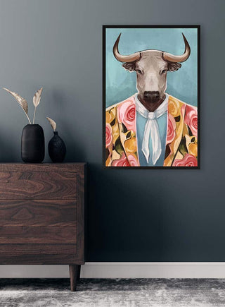 Framed print of a bull in a floral suit and cravat, hanging above a modern wooden dresser.