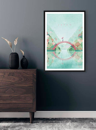 Framed Japan travel poster by Henry Rivers featuring a red bridge and mountains, displayed above a dark wood dresser.