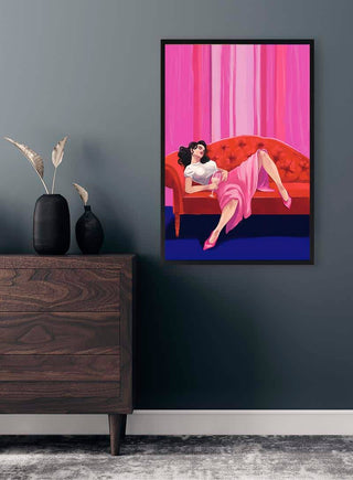 Framed artwork of a woman in pink lounging on a red sofa, displayed above a dresser in a modern room.