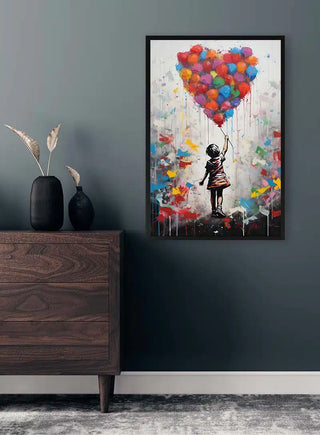 Banksy-inspired art of a girl reaching for heart-shaped balloons, displayed above a wooden dresser in a modern room.
