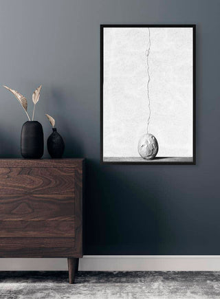 Cracks by Giorgio Toniolo framed on a gray wall above a wooden dresser with vases and dried plants.