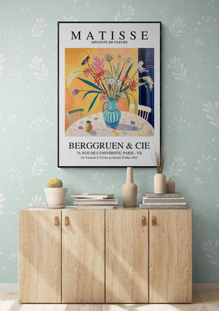 Framed Matisse Vase and Flowers artwork above a wooden cabinet in a modern, light-filled room.