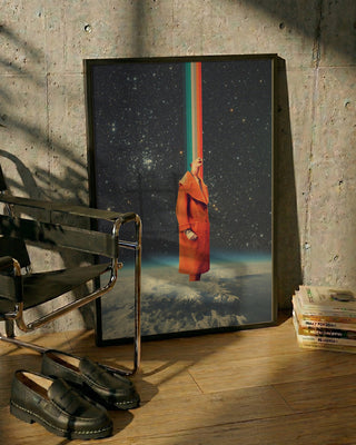 Framed Spacecolor - Frank Moth artwork with a surreal cosmic scene, resting on a wooden floor by a chair.