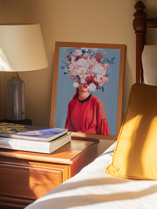 Framed "We Gathered In Spring" by Frank Moth on a bedside table with books and a lamp.