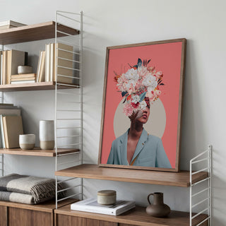 Framed "Searching for Sunrise" by Frank Moth on a shelf, featuring a floral collage portrait against pink background.