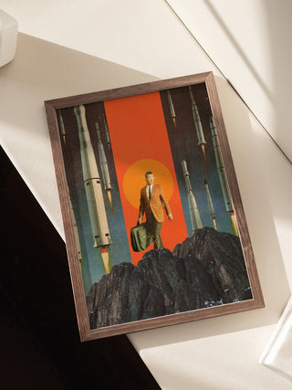 Framed print of "The Departure" by Frank Moth, featuring a suited man with rockets and an orange sun backdrop.