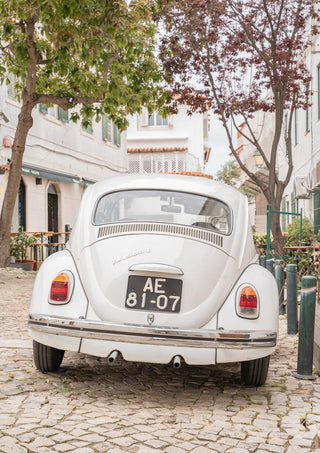 Vintage white car parked on a cobblestone street in Cascais, ideal for Driving Cascais experiences.