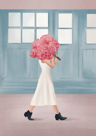 Woman in a white dress holding a bouquet of pink flowers, walking past blue windows.