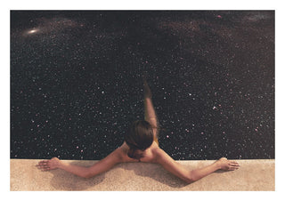Holynight by Fran Rodriguez - a figure lying with arms outstretched on pale sand under a field of stars
