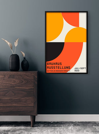 Bauhaus Orange Plakat on a wall above a dark wood dresser with minimalist decor in a modern room.