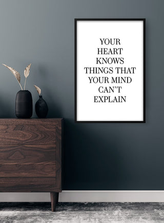 Minimalist "Your Heart Knows" poster hanging above a dark wooden dresser in a modern room.