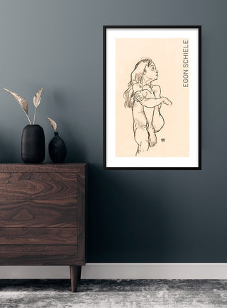 Framed print of Egon Schiele's "Seated Nude Girl Clasping Her Left Knee" (1918) on a modern interior wall.