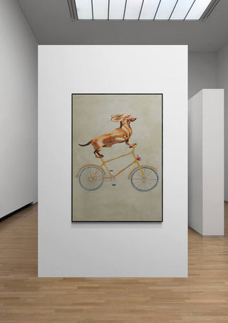 Art print of a dachshund riding a bicycle, displayed in a modern gallery setting.