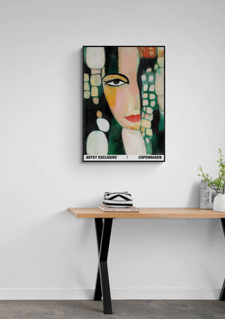Framed "Femininity" by Martin Zen featuring an abstract female portrait, displayed above a modern wooden desk.