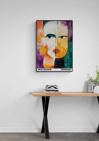 Colorful abstract portrait artwork "Duality" by Martin Zen, framed and hanging above a wooden table.