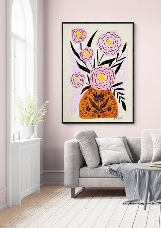 Framed print of pink flowers in an orange vase hanging above a gray sofa, styled for Pink Maxi Flower Vase - Baroo Bloom.