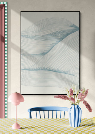 Framed "Ocean in lines 02" artwork with blue wave patterns hanging above a table with flowers in a striped vase.