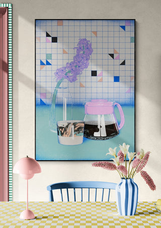 A framed print of a coffee drip pot and cup on a pastel table, displayed above a dining area with flowers.