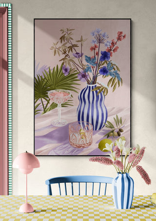 Framed "Lilac Summer - Goed Blauw" art print with striped vase and floral arrangement above a pastel dining table.