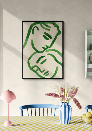 Framed Tender Embrace artwork with green line art of two faces, displayed above a dining table with flowers.