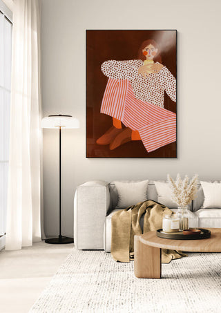 Framed "Woman With the Cup of Tea" by Bea Muller displayed above a modern living room sofa.