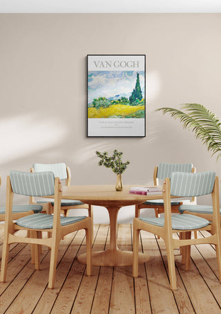Framed Van Gogh "Wheat Field" art print displayed above a wooden dining table with four chairs.