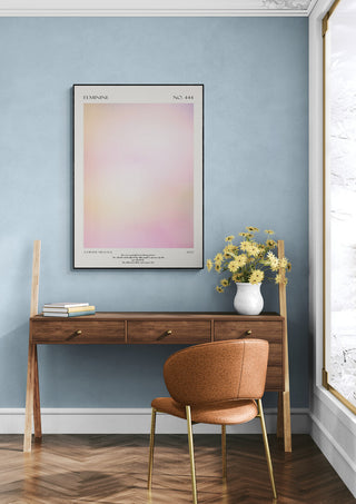 Feminie art print displayed above a wooden desk with flowers in a modern, light-filled room.