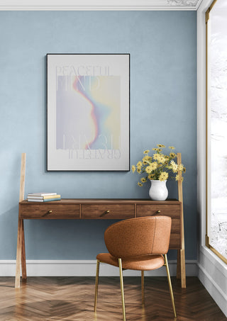 Minimalist workspace with a framed Peaceful Mind art print, wooden desk, yellow flowers, and modern chair.
