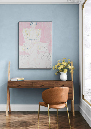 Framed "Gamer Girl" artwork on blue wall above wooden desk with vase of yellow flowers and brown chair.