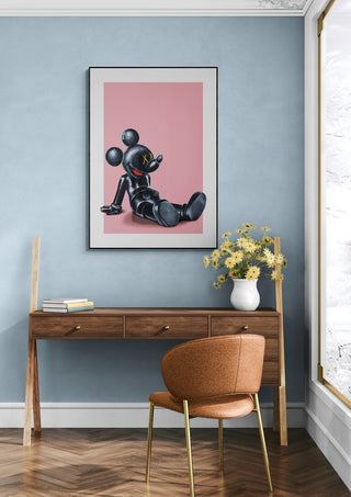 Framed Kawsey Relax - Daniel Leo artwork on pink background displayed above a modern desk in a stylish room.