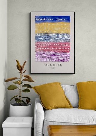 Framed print of Paul Klee's "Old City" above a white sofa with yellow pillows in a modern living room.
