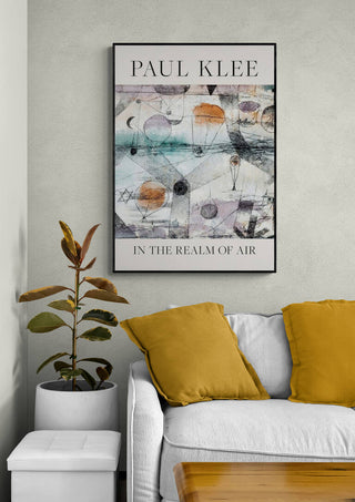 Framed "In the Realm of Air 1917" by Paul Klee hanging above a sofa with yellow cushions.