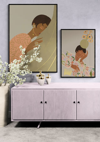 Two framed "The Introvert" by Arty Guava art prints displayed above a pink sideboard with vases and flowers.