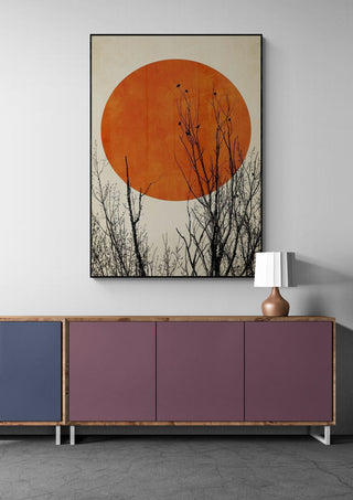 Winter Glow by Boris Draschoff on wall above cabinet, showing a large orange sun and silhouetted tree branches.