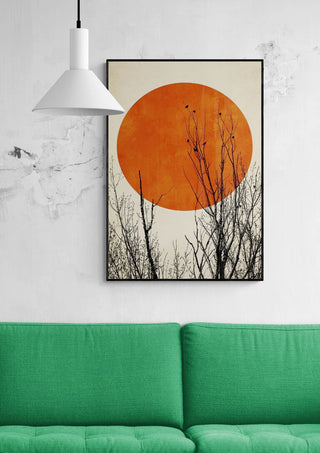 Winter Glow by Boris Draschoff art print featuring a large orange sun and bare tree branches above a green sofa.