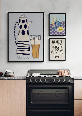 Framed “Bake it till you make it” print displayed above a stove in a modern kitchen setting.