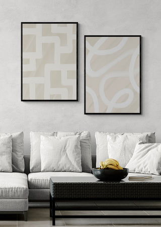 Two abstract Calm Gesture - Yuli art prints in black frames above a modern sofa with white cushions.