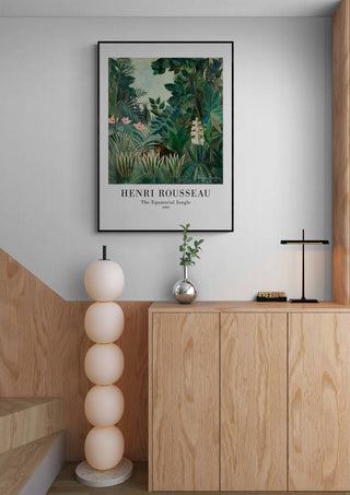 Framed print of "The Equatorial Jungle" by Henri Rousseau hanging above a modern wooden sideboard.