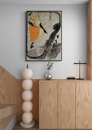 Framed Jane Avril by Toulouse-Lautrec art print displayed above a modern wooden cabinet in a stylish interior.