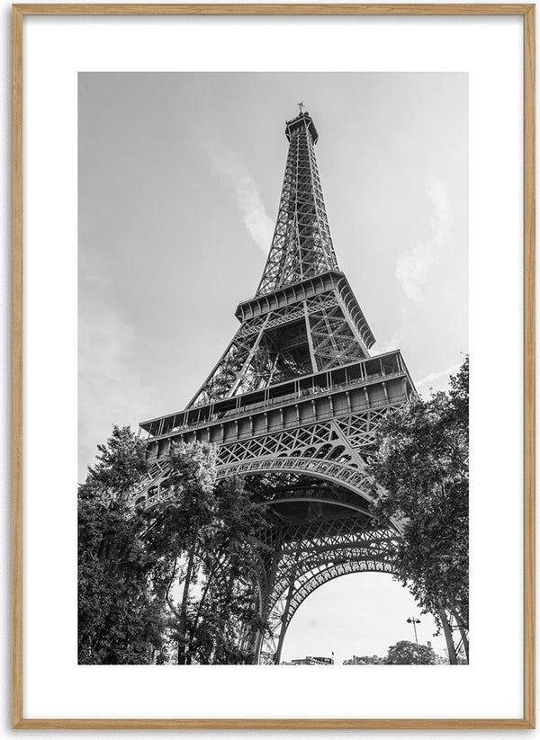 Black and white poster of the Eiffel Tower viewed from below, framed by trees against a clear sky.