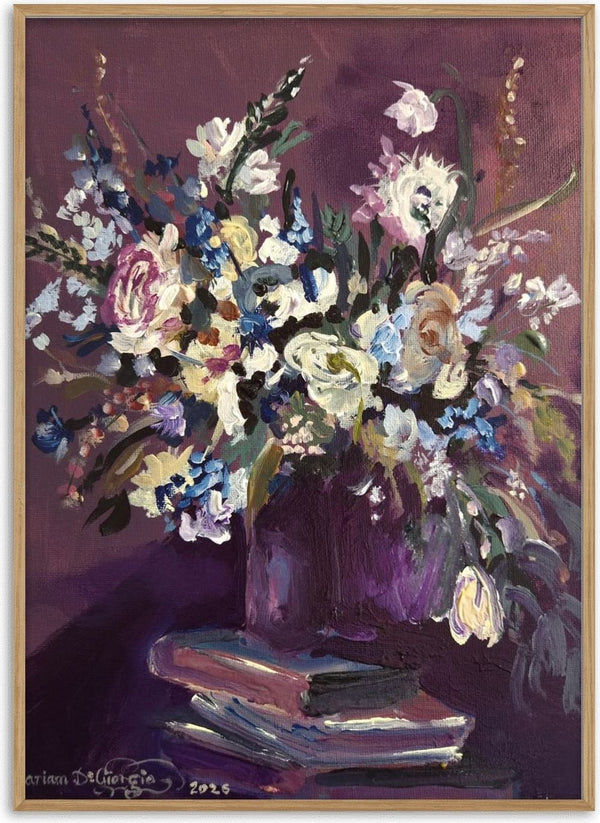February arrangement by Mariam De Giorgio — a bouquet of cream roses and blue blossom in a plum vase on stacked books against a deep purple ground.