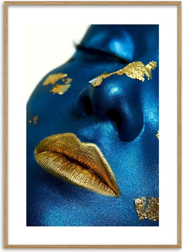 Close-up of blue-painted face with metallic golden lips and gold leaf accents, featured on a decorative poster.